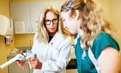 health professional looking at model knee with teen