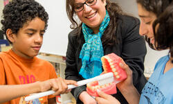 woman showing students model teeth