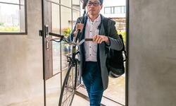 man carrying bicycle in to work